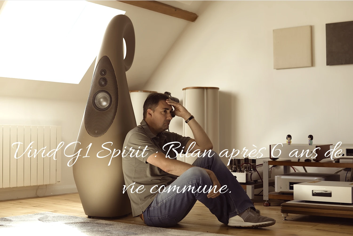 Joel CHEVASSUS est assis par terre, la tête posée dans sa main, contre une enceinte Vivid Audio G1 Spirit dans une pièce élégante. La superposition de texte en français indique qu'il s'agit du bilan sur ses enceintes après 6 ans de vie commune (par 1877.audio)