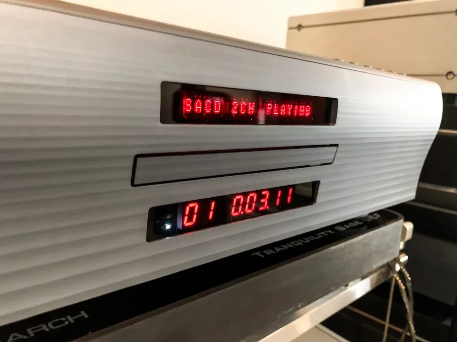 Un gros plan sur le transport CD/SACD Playback Designs MPT-8 affichant "SACD 2CH playing" ainsi que la piste actuellement jouée "01" et un minuteur de lecture de cette piste "0.03:11" (par 1877.audio)