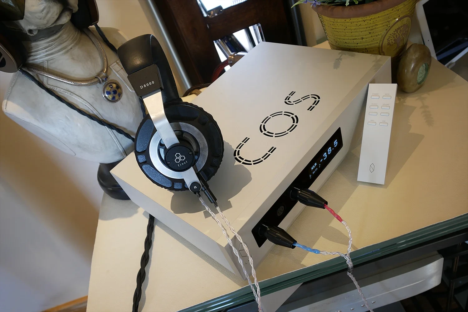 Amplificateur haut de gamme Cos Engineering D10 avec son logo découpé le-dessus connecté à une casque audiophile de marque Final (par 1877.audio)